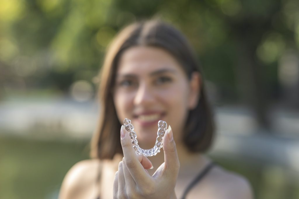 Beautiful smiling Turkish woman is holding an invisalign bracer